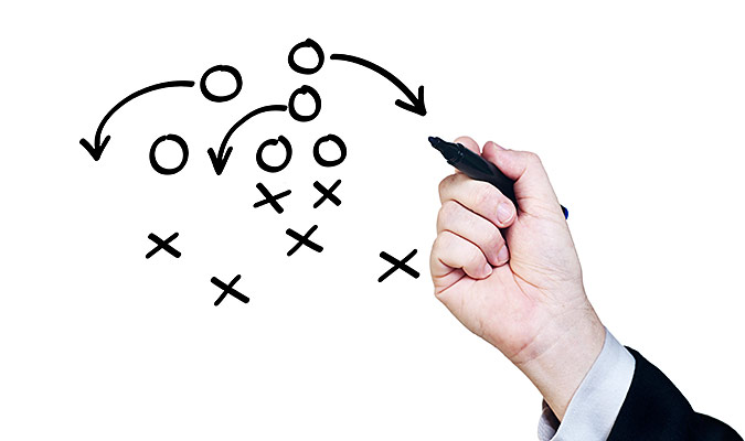 Man in a suit drawing out a diagram of football strategy.