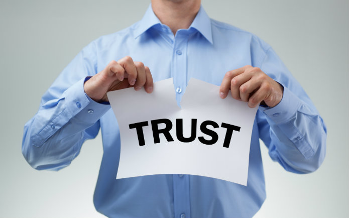 Image of a man ripping a paper that says "trust"