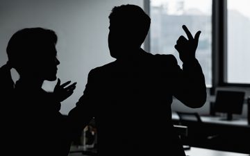 Silhouette of two business people gesturing and arguing in the office