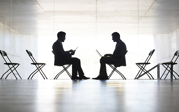 Silhouette of businessmen working in office, sitting across from each other